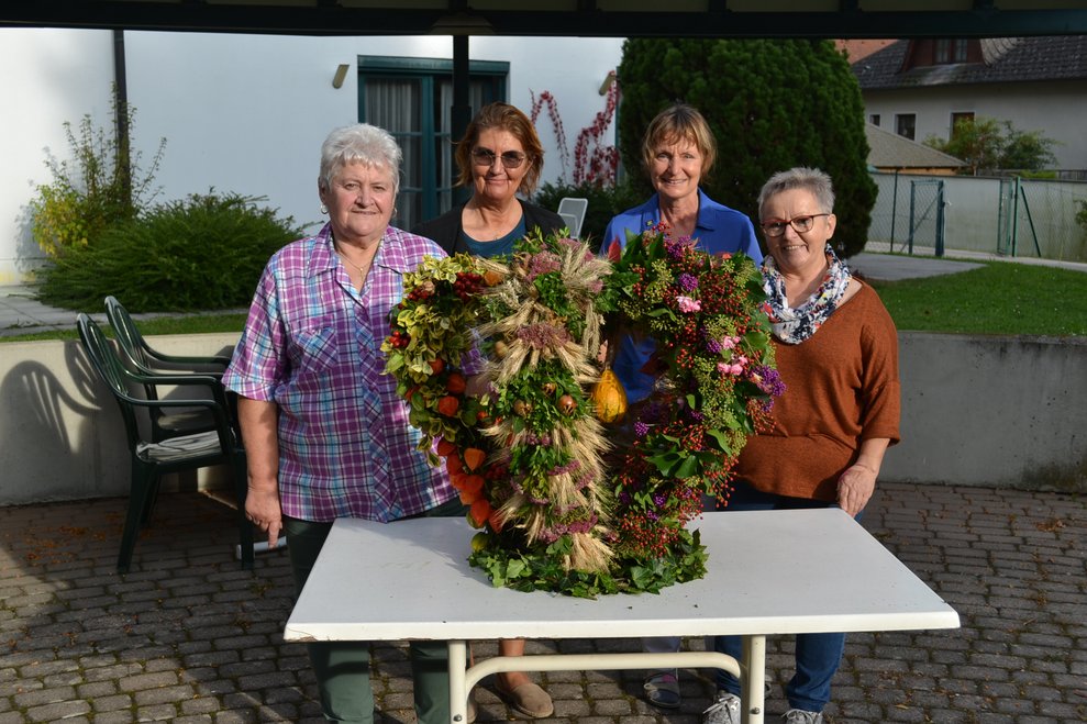 Damen stehen neben der fertigen Ertnekrone