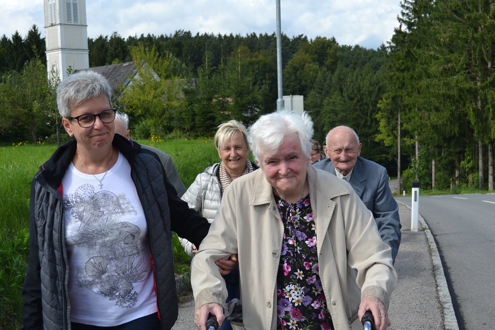 Heimbewohnerinnen und Heimbewohner marschieren mit 2 Pflegerinnen
