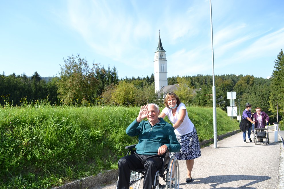 Betreuerin schiebt Heimbewohner mit Rollstuhl