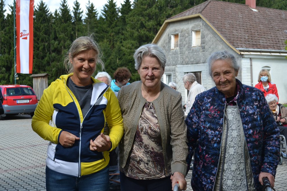 eine Pflegerin mit 2 Heimbewohnerinnen vor dem Gasthaus