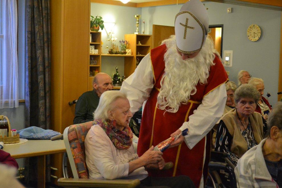 Der Nikolaus überreicht einer Dame ein Geschenk