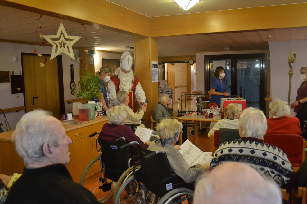 Der Nikolaus überrreicht einer Heimbewohnerin ein Geschenk 